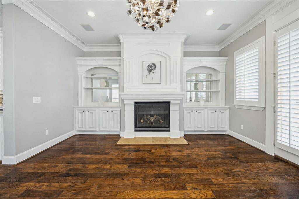 The living room(2nd floor) is beautifully appointed with custom cabinetry and detailed millwork surrounding a cast stone fireplace. Hardwood floors, crown molding, and designer lighting enhance the space. Step directly onto the balcony for a view of the backyard.