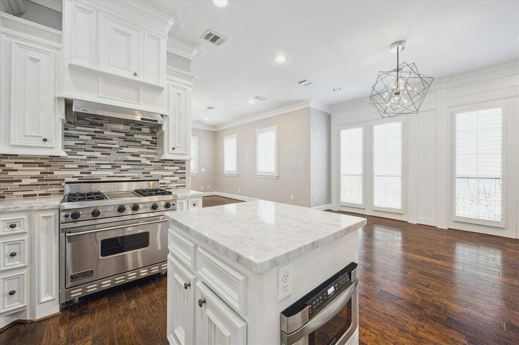 The kitchen features a professional-grade Viking gas range with a convection oven, four burners, and a center griddle, along with a built-in microwave conveniently located in the island.