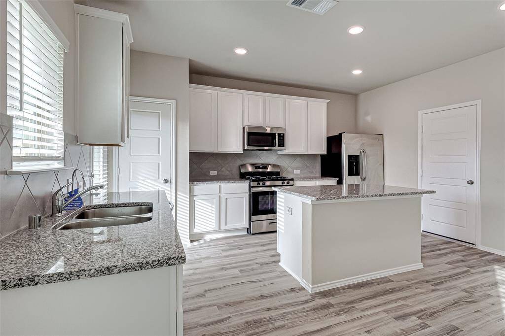 Alternate view of the kitchen, floors and recessed lighting carry throughout making the whole space feel as one