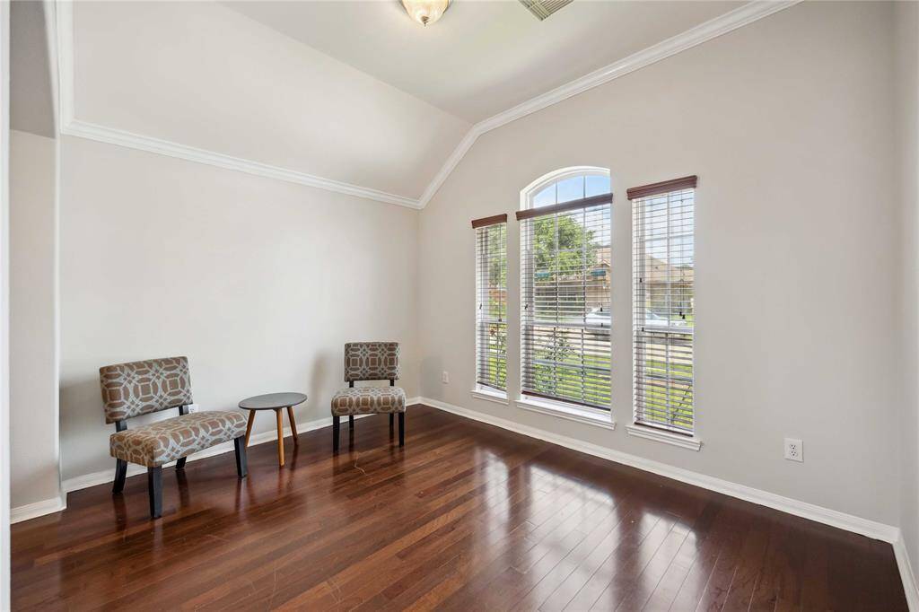 Formal living room features warm wood flooring and a spacious layout filled with natural light.