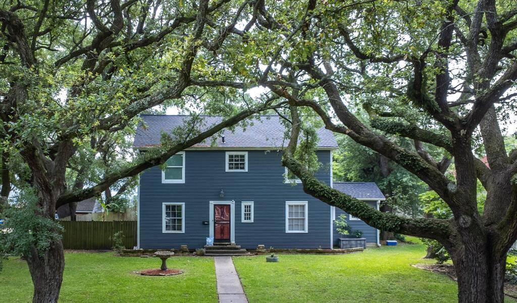 Charming home, beautifully framed by mature, sprawling oaks and a lush yard.