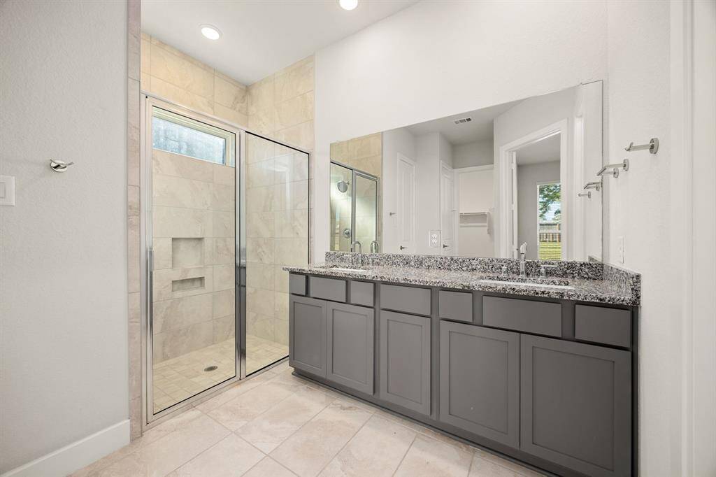 This primary bathroom is definitely move-in ready! Featuring a large walk-in shower with tile surround, dark stained cabinets with light countertops, spacious walk-in closet with shelving, high ceilings, custom paint, sleek and dark modern finishes.
