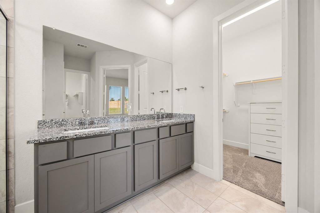 Step into a spa-like primary bath showcasing a double vanity with a large mirror, offering plenty of space and convenience for your daily routine.