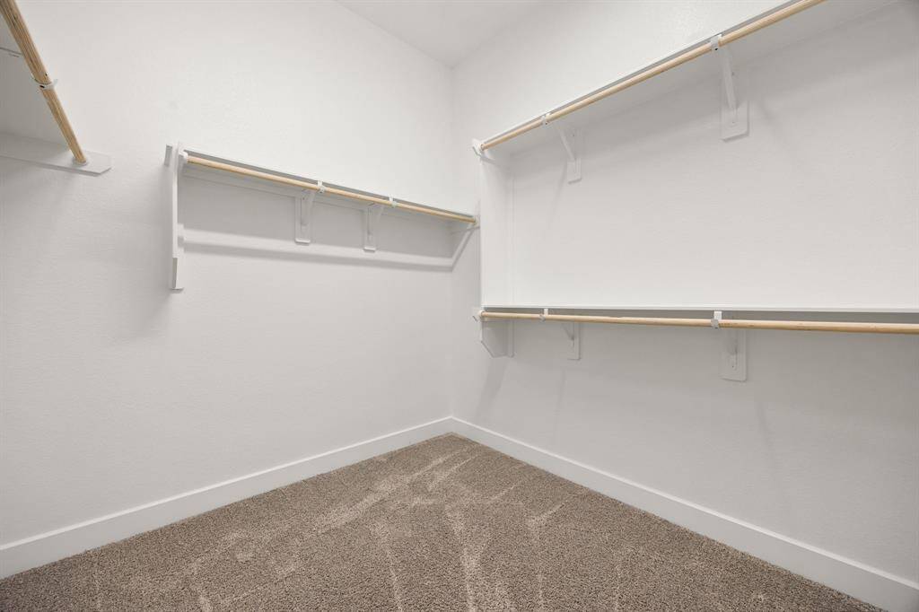 Step into a generously sized walk-in closet offering ample shelving, rods, and storage solutions—perfect for keeping your wardrobe neatly organized.