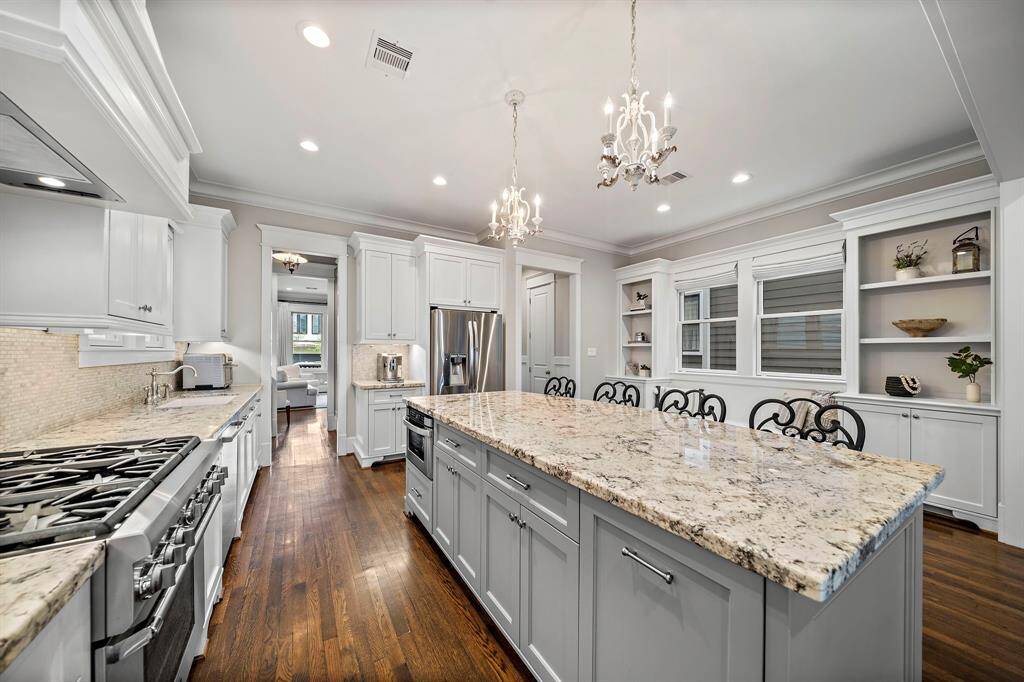 Spacious kitchen with a large gas range, tons of countertop space, pendant lights, an under-counter microwave, and impressive built-in bookshelves—perfect for cooking, gathering, and showcasing your favorite reads!