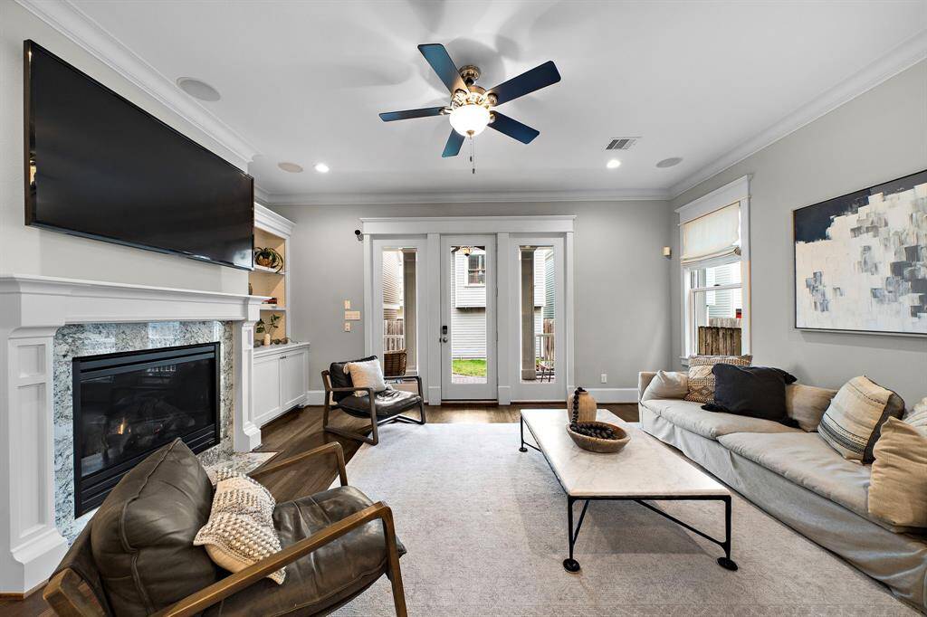 Another view of the living room showcasing elegant crown molding and a door leading to the backyard—bringing in natural light and easy access to outdoor living.