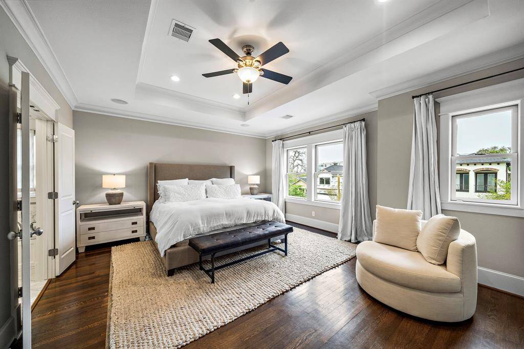 The primary bedroom on the second floor features trayed ceilings, crown molding, hardwood floors, and an abundance of natural light. With a spa-like feel, it overlooks the front elevation of the home, adding depth and charm.