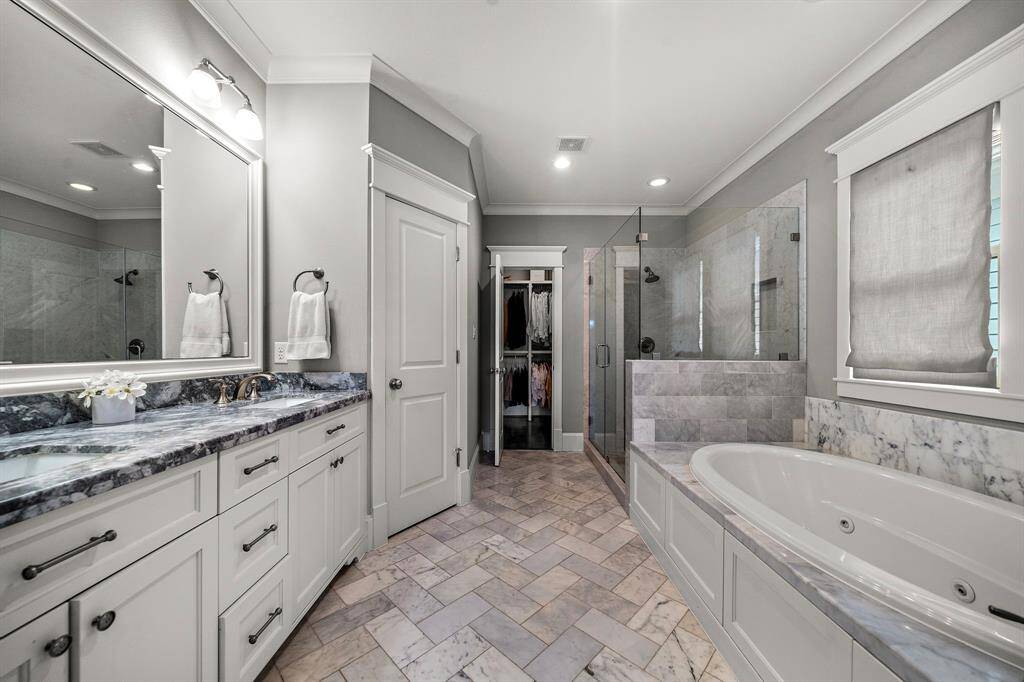 The spacious primary bathroom features double vanity sinks, a relaxing garden tub, a walk-in shower, and a private water closet. Beautiful finishes throughout, including elegant lighting, stunning countertops, and crown molding, add a touch of luxury.