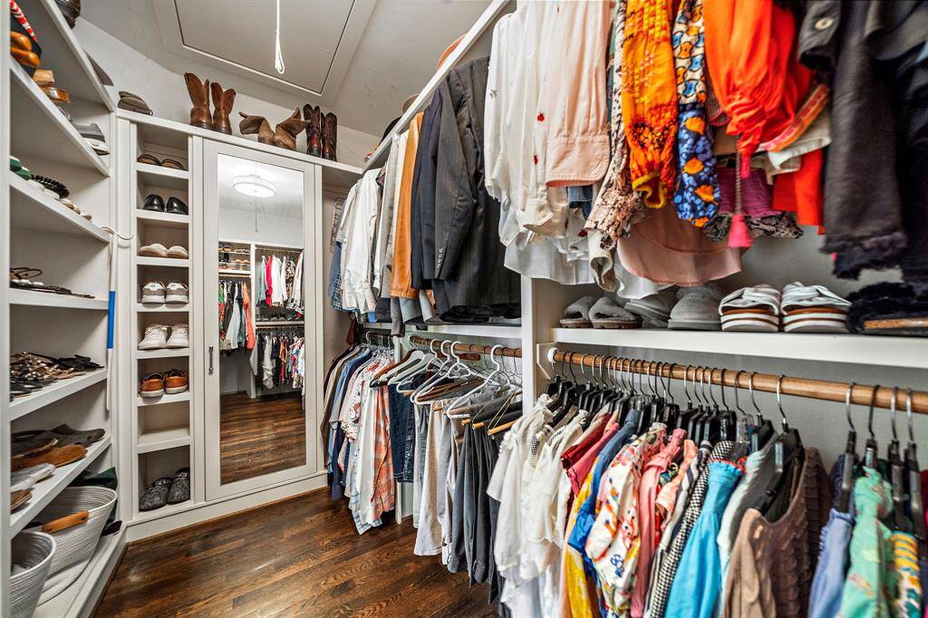 The primary closet offers hardwood floors, built-in shelves for ample storage, and a full-length mirror—combining function and style in one space.