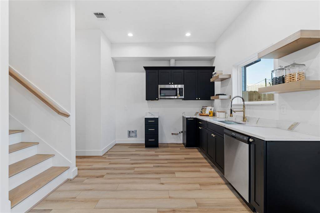 From this perspective, the kitchen's modern design shines, complemented by the view of the sleek staircase leading to the second floor. The open layout enhances functionality while maintaining a sense of connection throughout the home.