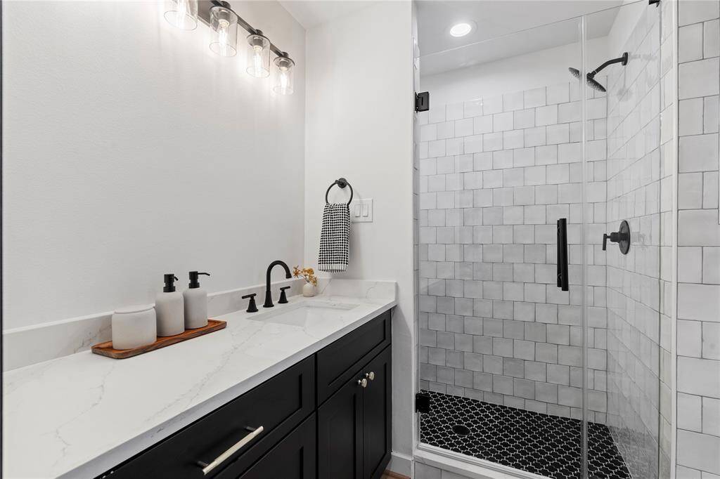 With its beautifully crafted walk-in shower and stunning quartz countertop, this primary bathroom exudes modern elegance. The sleek sink and refined details create a seamless, sophisticated space, perfect for relaxation.