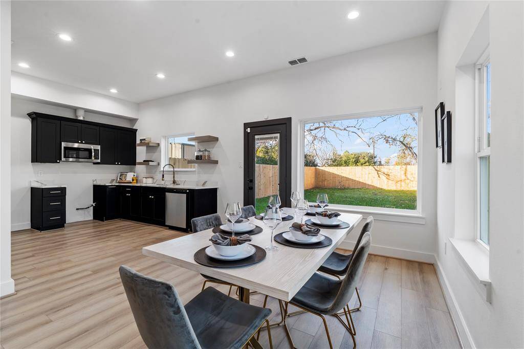 Step into the dining and kitchen area, where natural light fills the space through large windows and a glass door leading to the backyard.