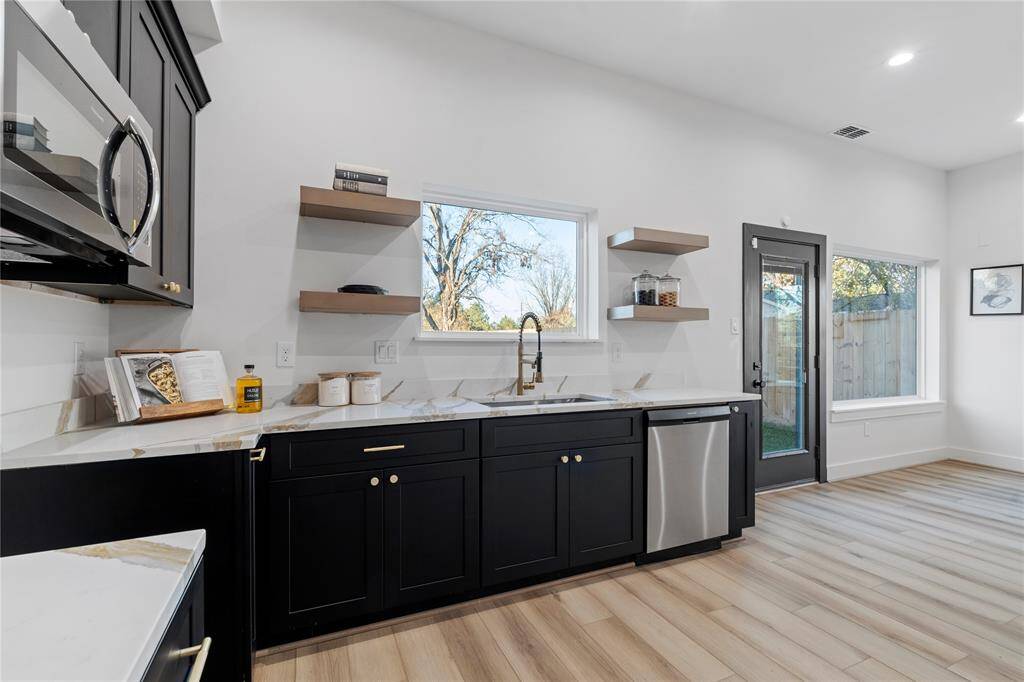 The modern kitchen features sleek black cabinetry and open shelving, offering both style and functionality. This space is perfect for sharing meals and making memories.