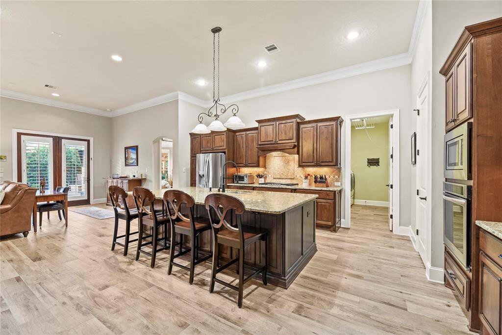 Incredible island kitchen features granite countertops, under cabinet lighting, tile backsplash, stainless steel appliances and a gas cooktop.