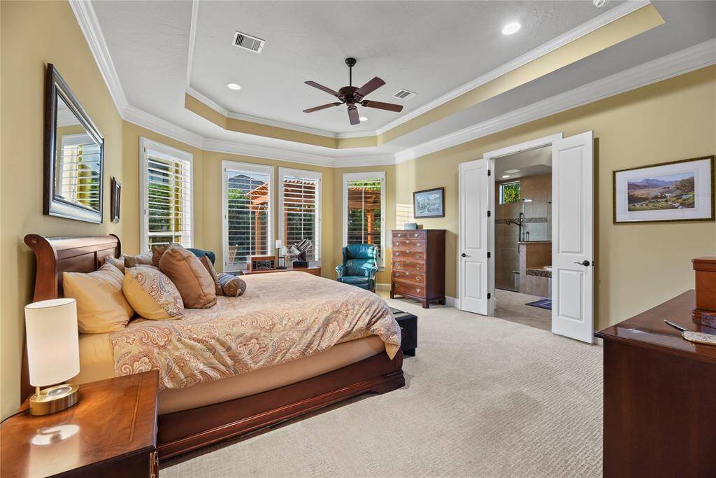 The primary retreat features an en-suite bathroom and sitting area with backyard views.