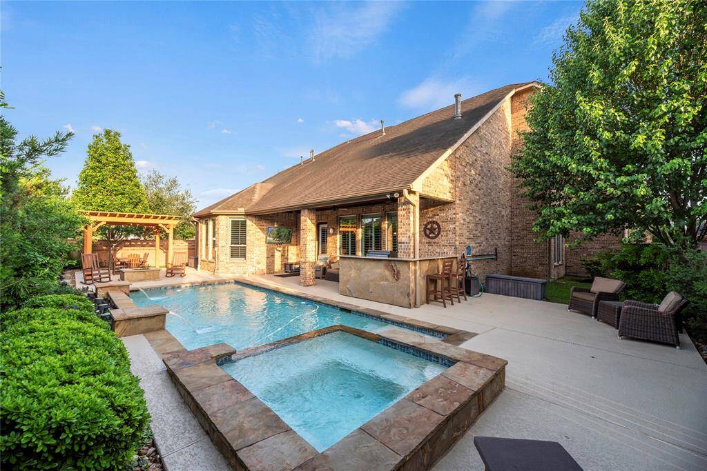 Backyard oasis features a sparkling pool/spa, Pergola, fire pit, covered patio and outdoor kitchen.