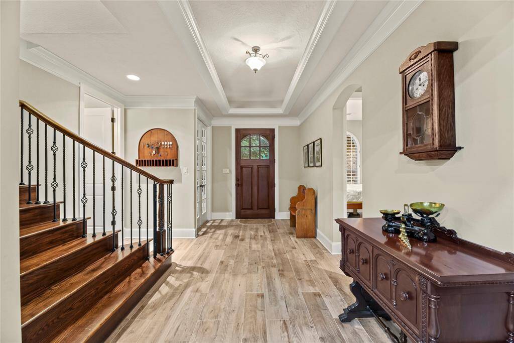 Inviting front entry boasts beautiful wood-look tile flooring, crown molding, tray ceiling and neutral paint color.