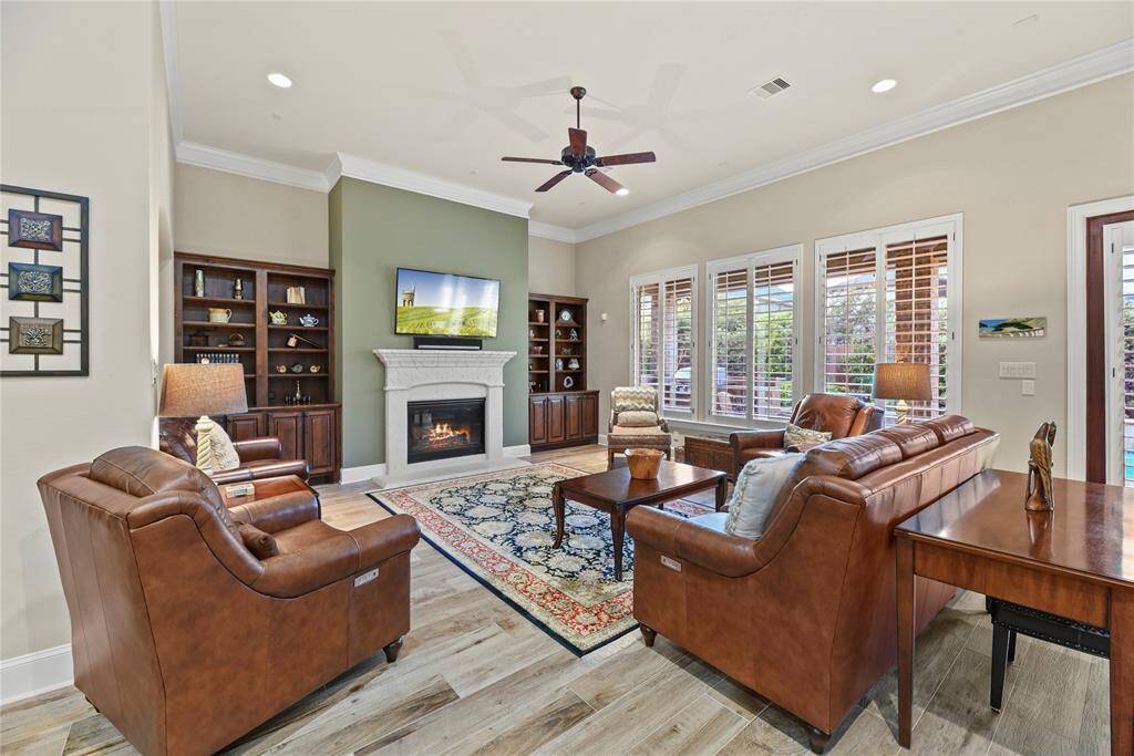 Spacious family room offers wood-look tile flooring, crown molding, ceiling fan, cozy fireplace and custom built-ins. Window shutters throughout!