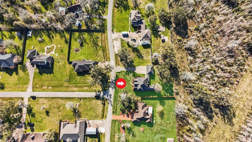 The aerial view of this stunning property offers a breathtaking perspective of its expansive lot. Nestled in the serene countryside of Brazoria, the property showcases wide-open spaces with mature trees and a gently rolling landscape, perfect for outdoor enthusiasts or those seeking peaceful country living.