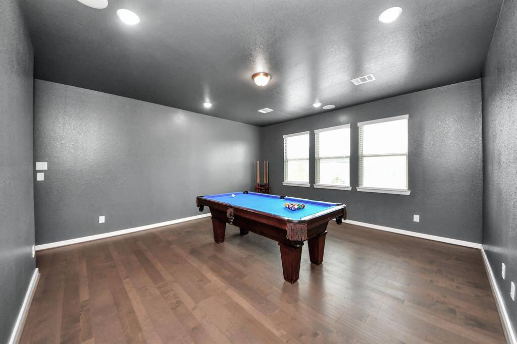 The game room features beautiful floors, custom paint, recessed lighting, and large windows.