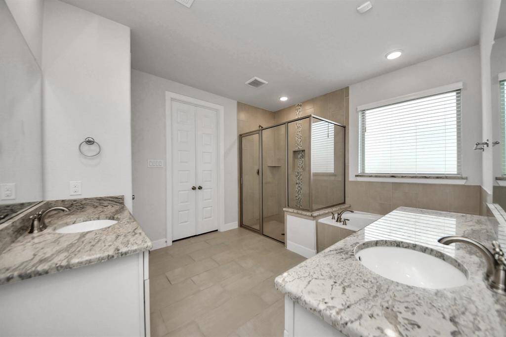 The primary bathroom features tile floors, dual sinks, walk-in shower, and separate tub.