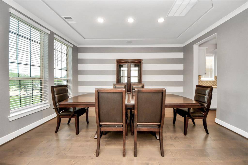 This dining room is bathed in naturallight streaming through expansivewindows and features recessed lighting, wood flooring, and custom paint with accent wall.