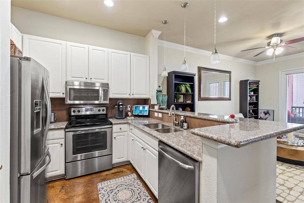 This galley kitchen offers plenty of room and Features include granite countertops, tiled backsplash, Stainless Steel appliances, crisp white cabinets, and recessed lighting.