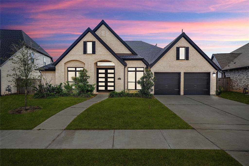 This beautiful home features a modern design with a brick exterior. It includes a spacious three-car garage and a welcoming front walkway surrounded by well-maintained landscaping.