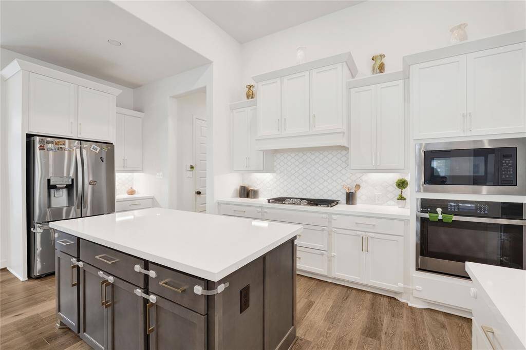 The kitchen island houses even more cabinets and a very large countertop space for preparing and serving food.