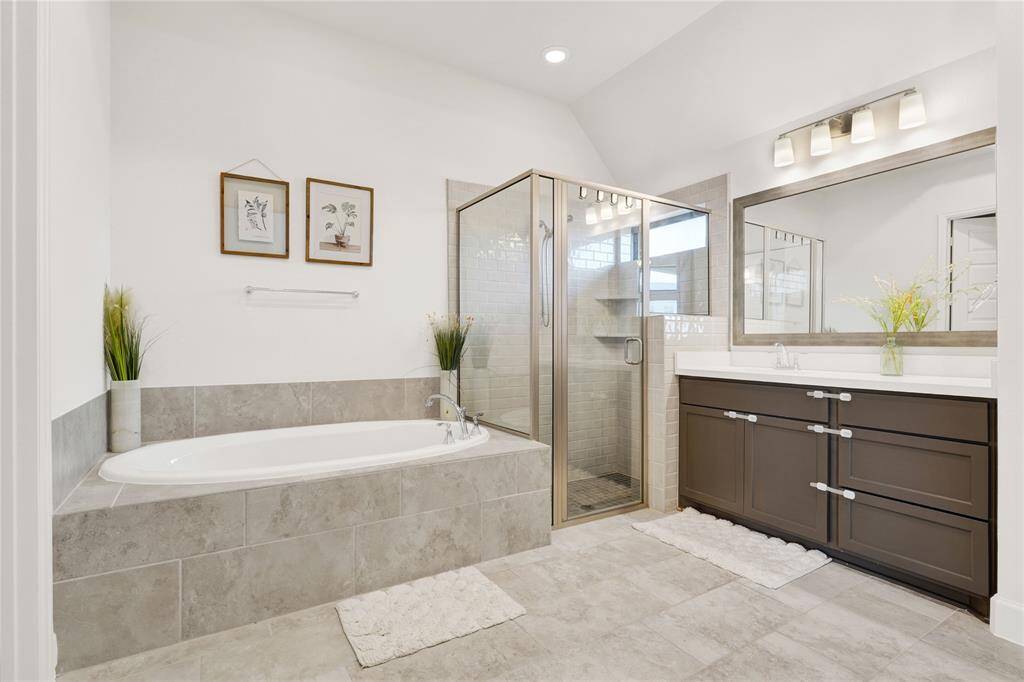 Primary bathroom featuring a standing shower with a bench, a separate soaking tub. This bathroom has two vanities and two closets.
