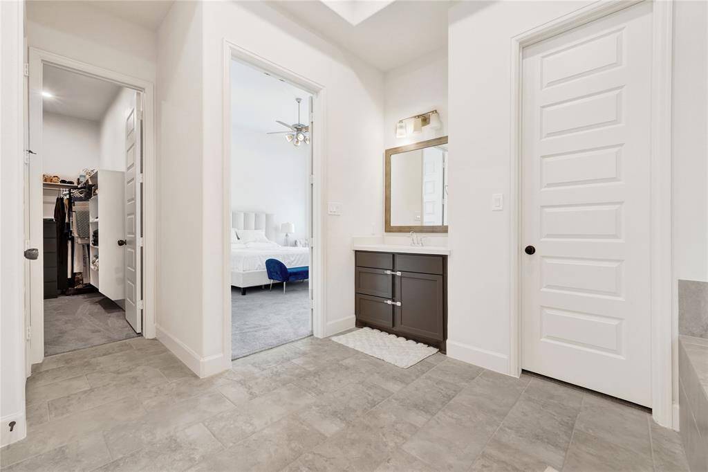 Primary bathroom featuring a standing shower with a bench, a separate soaking tub. This bathroom has two vanities and two closets.