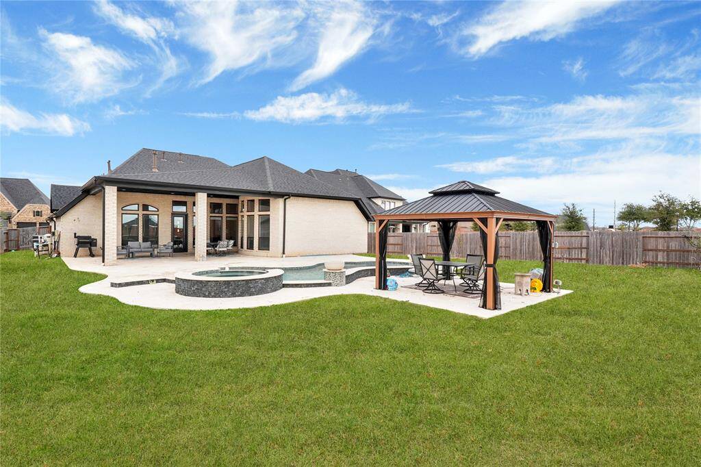 The expansive, oasis-style backyard boasts a luxury custom-built pool with a hot tub, all elegantly surrounded by a travertine patio. A charming gazebo offers the perfect retreat for relaxation and outdoor enjoyment.