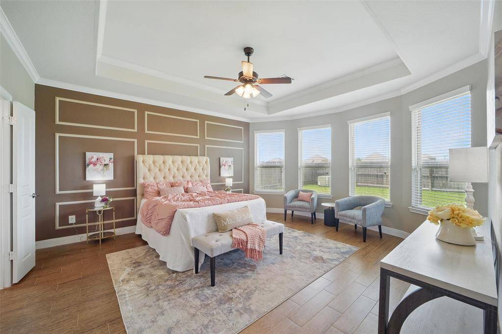 Primary Bedroom with bay windows, trey ceiling, feature wall, and ceiling fan.