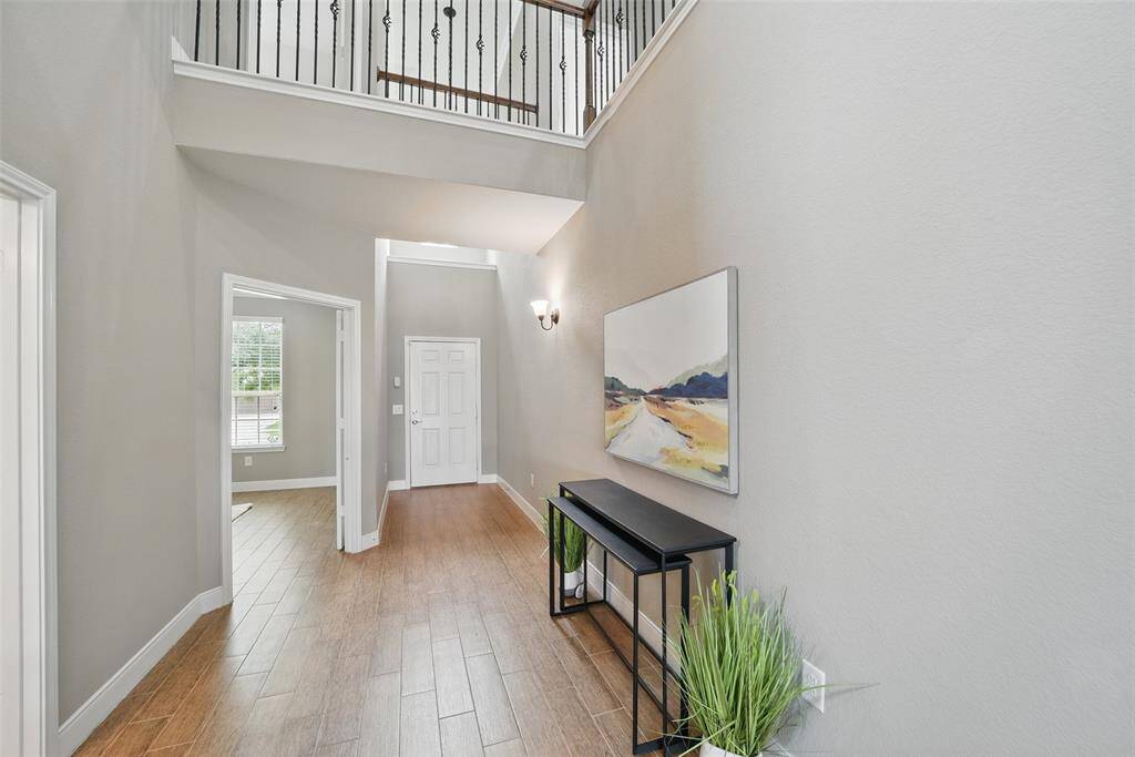 Gorgeous two story entryway with ceramic tile wood-looking flooring and stunning rod iron stair case railing on the breezeway above.