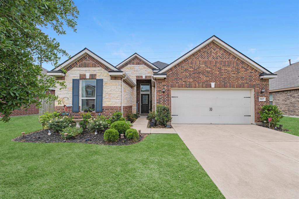 This charming single-story home features an upgraded brick and stone exterior with a well-manicured front yard. It includes a two-car garage and a welcoming entrance.