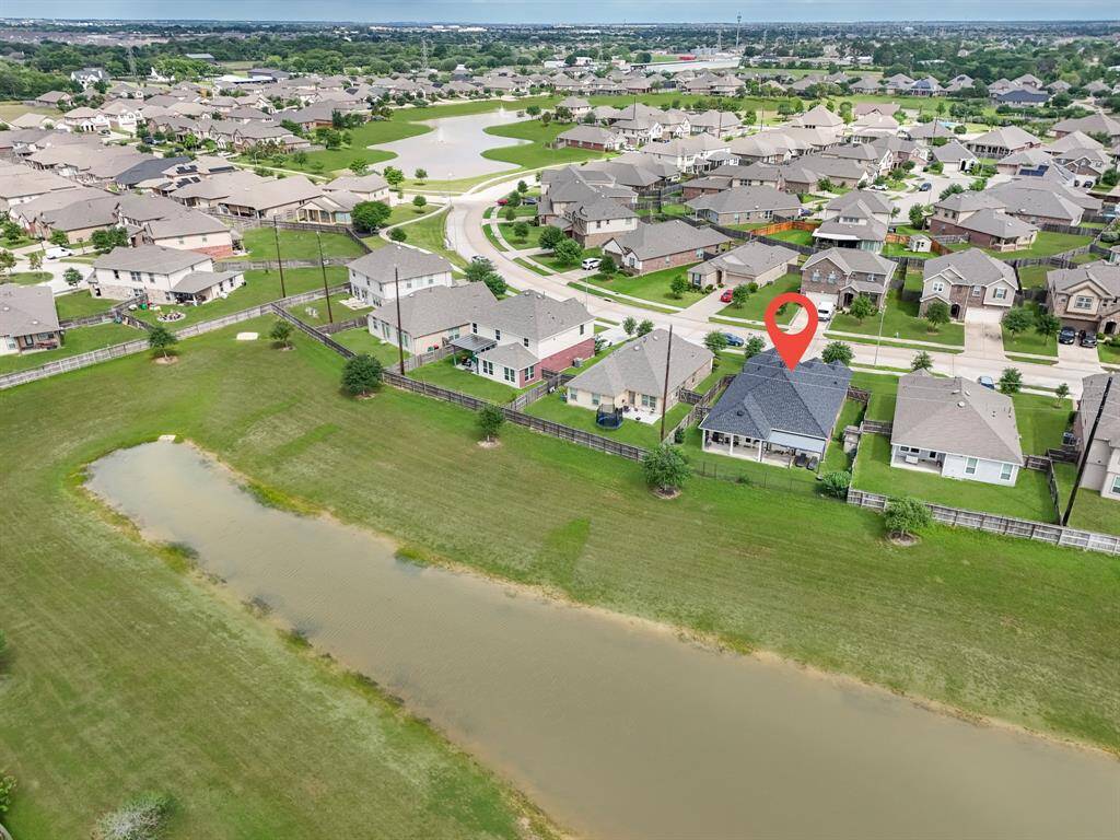 Aerial view of the neighborhood showcasing the subject home. The area features well-maintained houses, green spaces, and winding roads, offering a tranquil suburban setting.