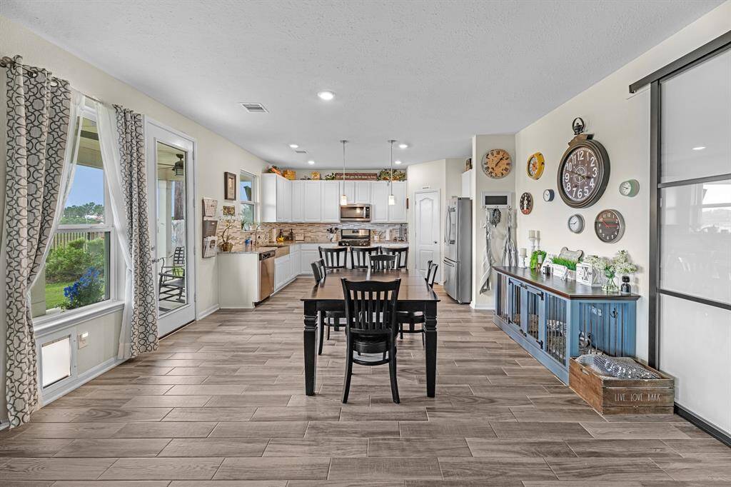 This photo showcases the bright, open-concept kitchen and dining area. Large windows and a glass door offer ample natural light and a view of the outdoor greenery, creating an inviting and functional dining area.