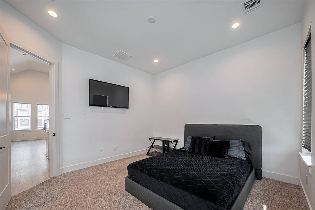 This upstairs primary bedroom offers a peaceful retreat with plush carpeting, modern recessed lighting, and direct access to the main living area—ideal for guests or a secondary suite.