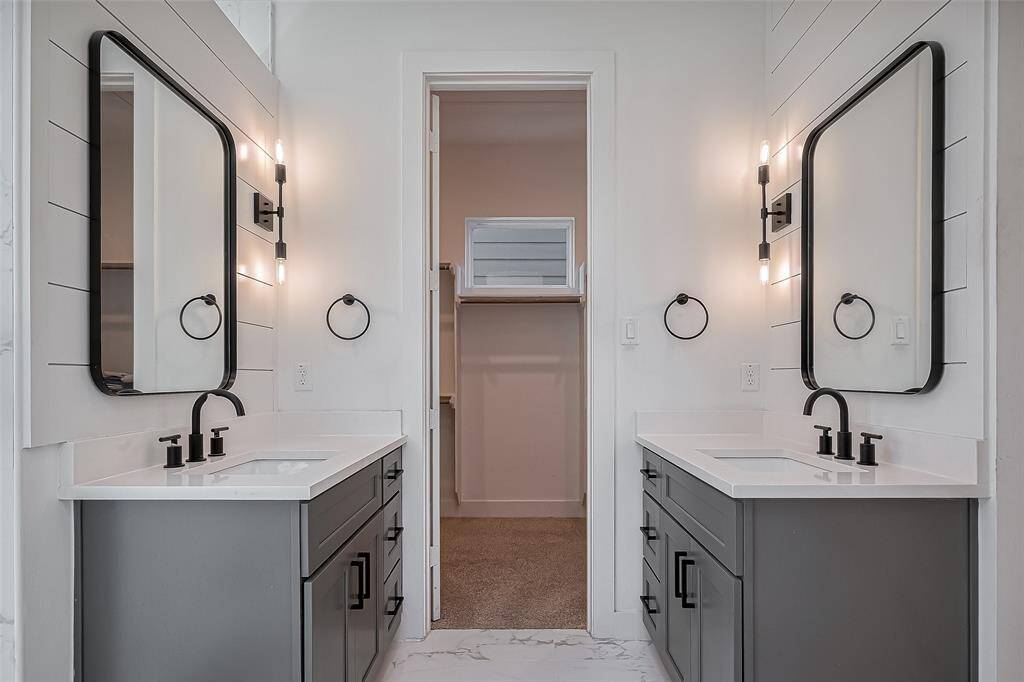 This luxurious en-suite bath boasts dual vanities with quartz countertops, matte black hardware, and stylish lighting—offering the perfect blend of elegance and practicality with direct access to a spacious walk-in closet.