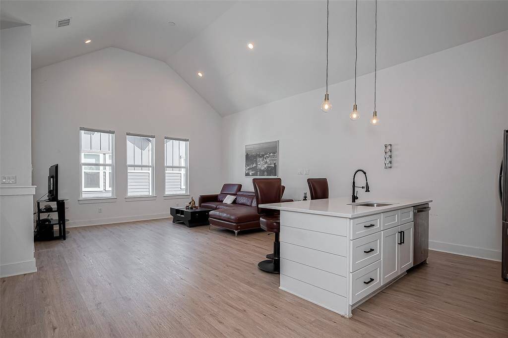 The open-concept layout seamlessly connects the living area to a stylish kitchen with pendant lighting, a large island with bar seating, and modern finishes—ideal for hosting and everyday living in style.