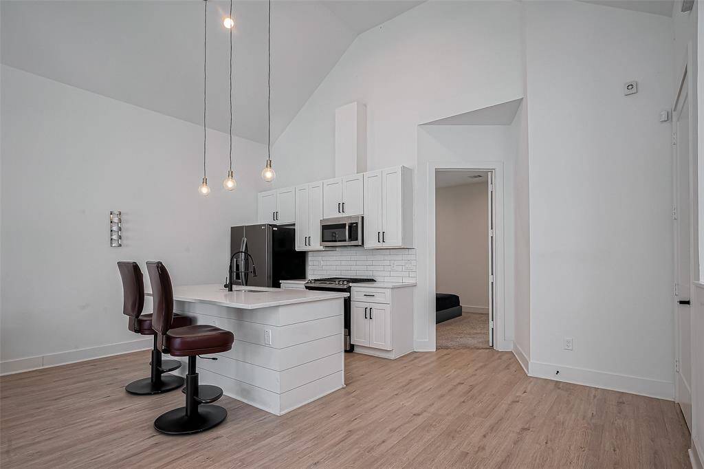 This modern kitchen is a chef’s dream, featuring stainless steel appliances, crisp white cabinetry, a subway tile backsplash, and a center island with bar seating—blending functionality and design for the perfect culinary space.