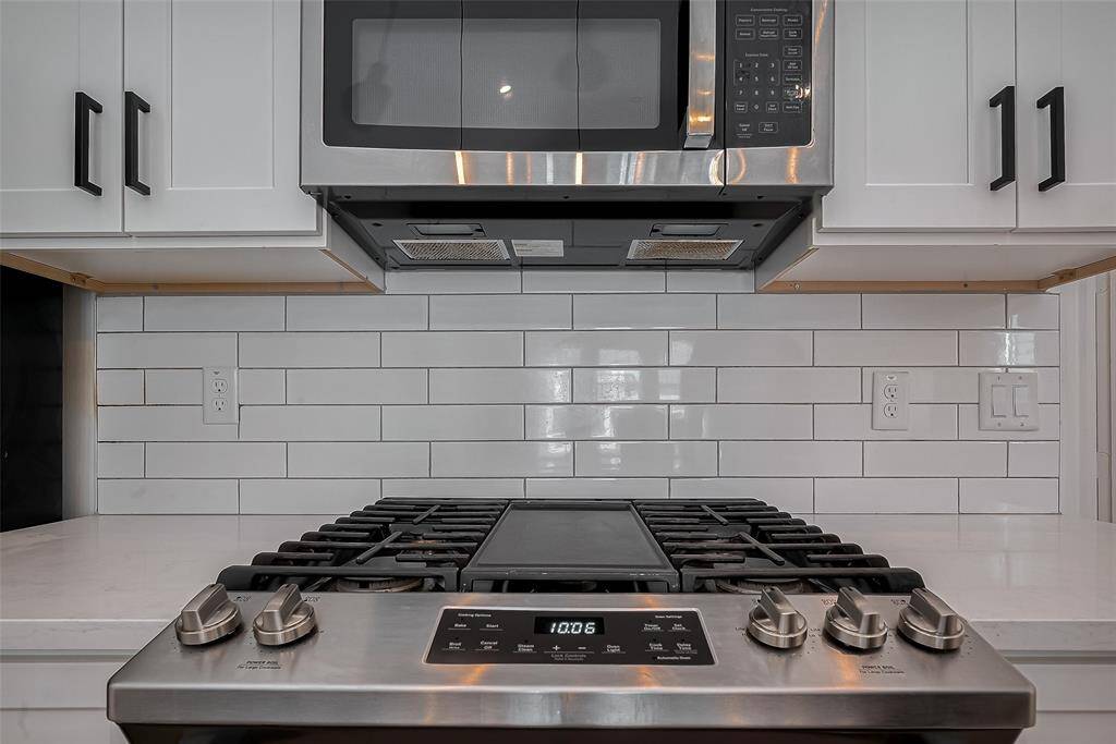 Experience elevated cooking with a sleek stainless steel gas range and built-in microwave, set against a classic white subway tile backsplash—bringing both style and performance to the heart of the home.