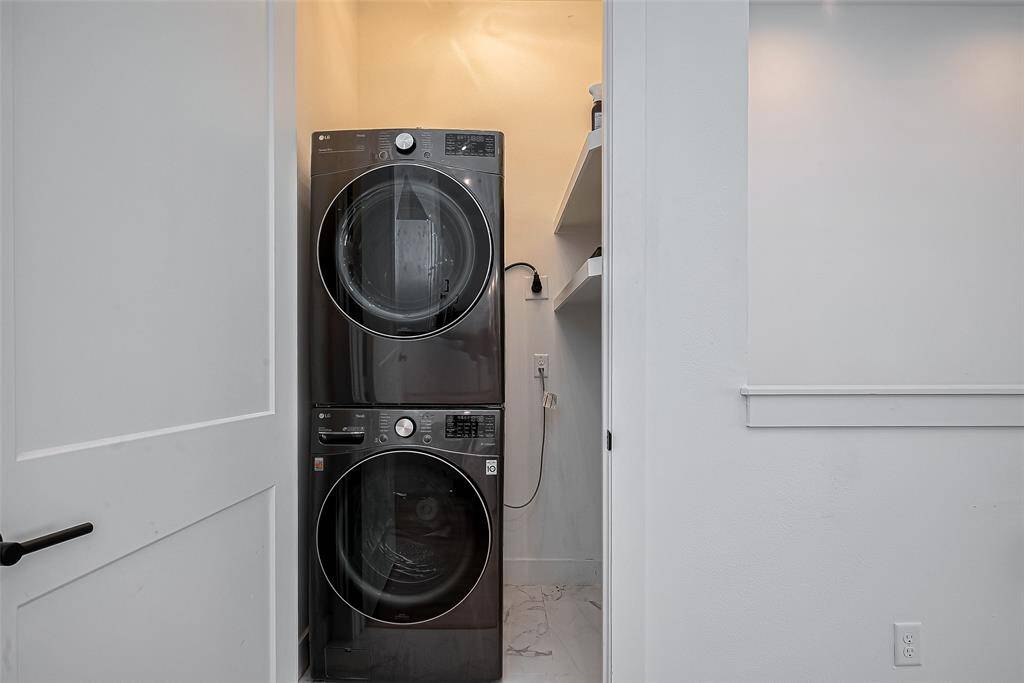 Tucked away for convenience, this dedicated laundry space features a sleek front-load washer and dryer set with built-in shelving—making household chores easier and more efficient.