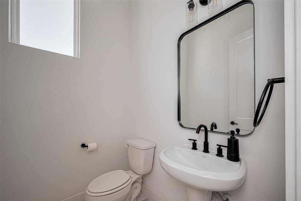 This modern powder room makes a stylish statement with bold matte black fixtures, a sleek pedestal sink, and a large framed mirror—perfect for guests and everyday use.