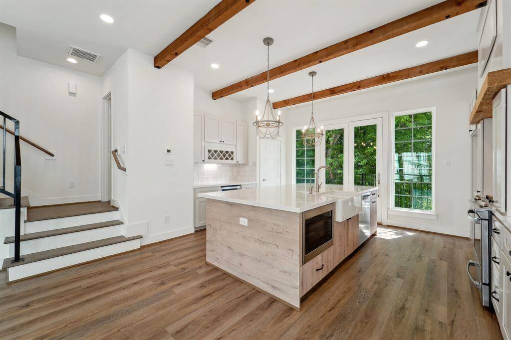 Beautiful Wood beams and chandelier lighting over the island with farm style sink and built in microwave.