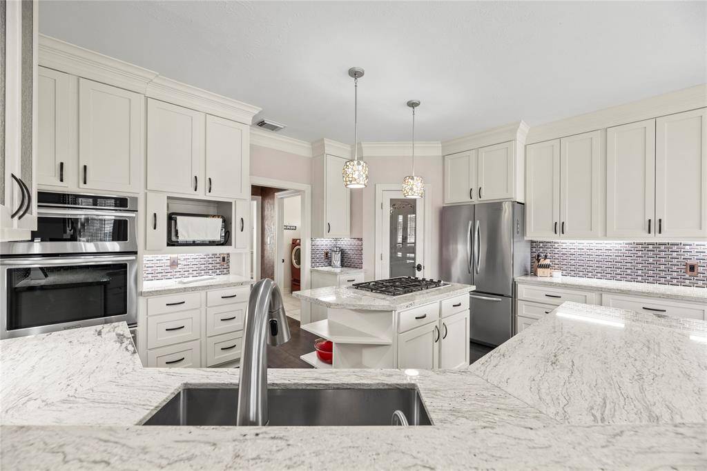 Cooking is a breeze with loads of prep space and an amazing layout. A custom backsplash and complementary granite countertops give a cohesive feel in this gourmet kitchen.