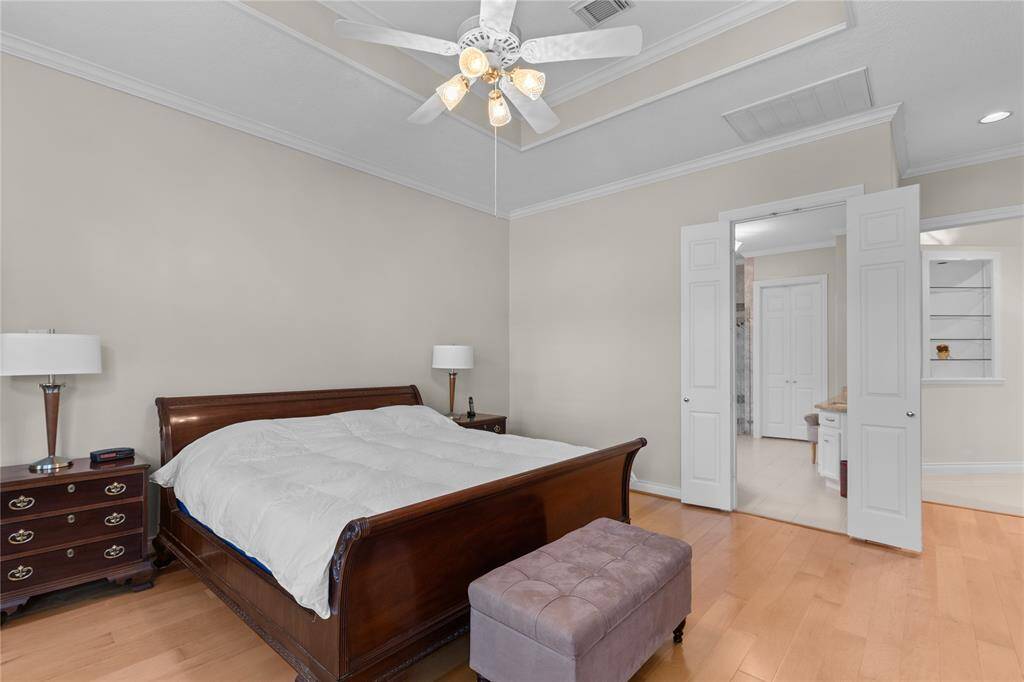 The primary bedroom is a serene sanctuary featuring elegant crown molding and engineered wood flooring enhances the room's warmth and richness