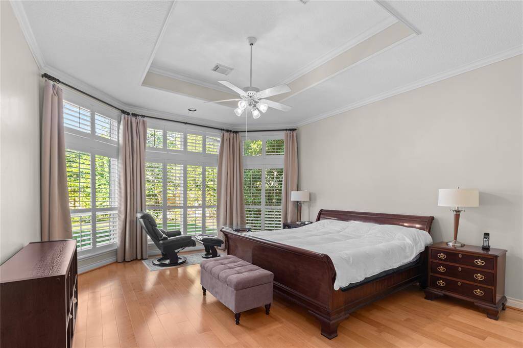 Another view of the primary bedroom with a large massive plantation shutters windows that frame the view of the backyard.