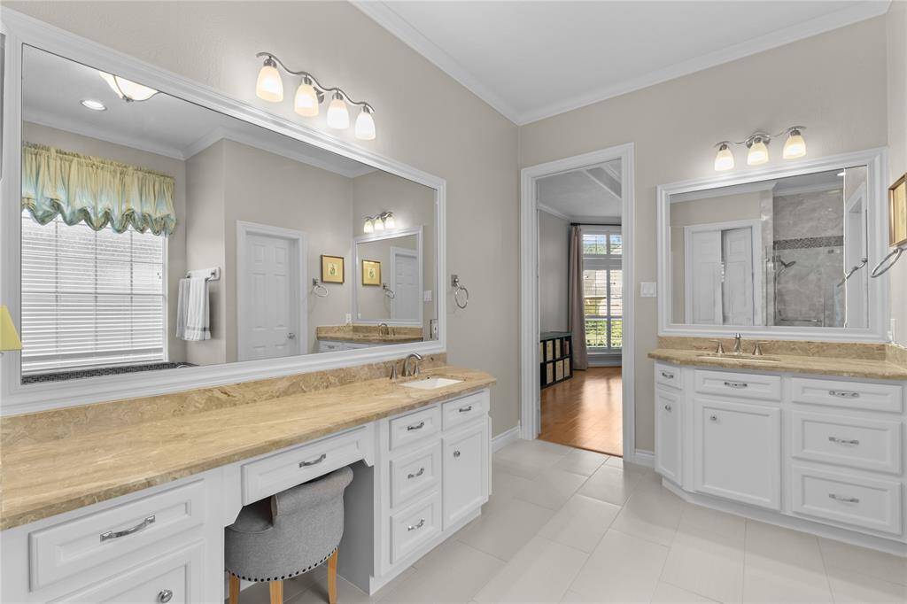 The primary bath features two wall-mounted mirrors illuminated by elegant light fixtures.
