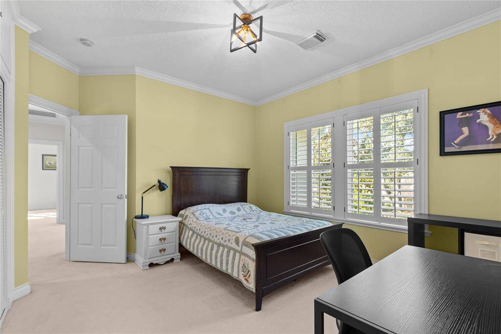 Second floor bedroom featuring high ceiling, and large plantation shutter windows that allow plenty of natural light to flood into the room.